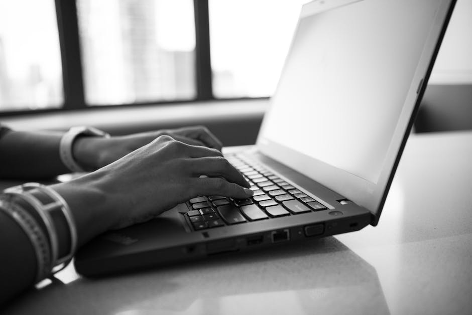 Hands typing on a laptop at a clean modern desk