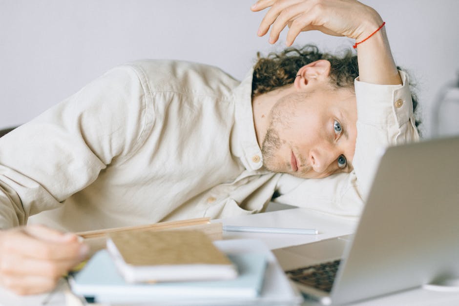 Tired office worker at a laptop on a cluttered desk
