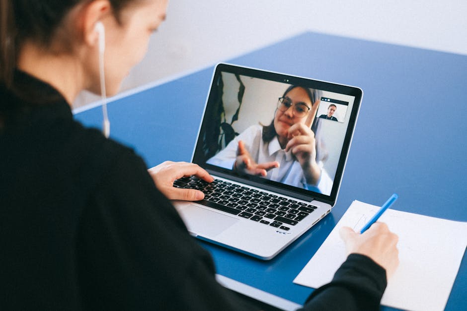 Person taking notes on a laptop during a video conference